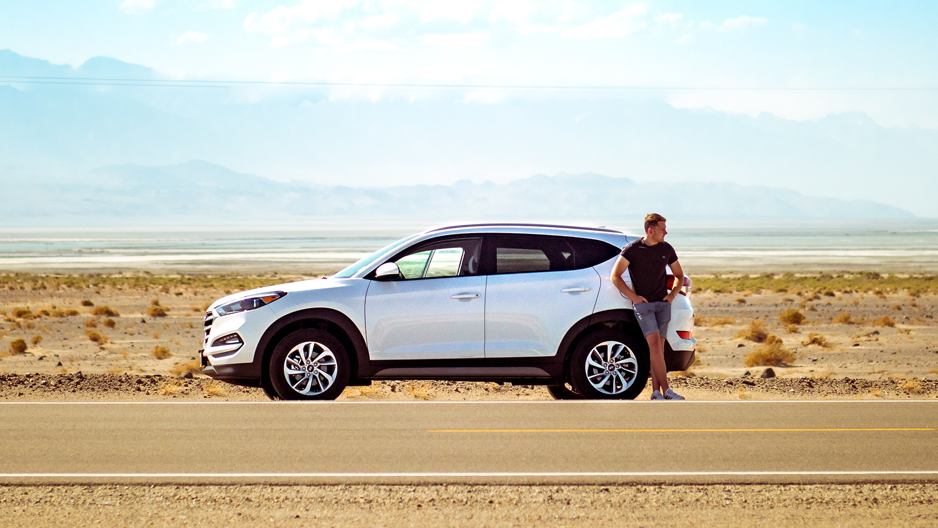 Image of a man standing by a car in the desert
